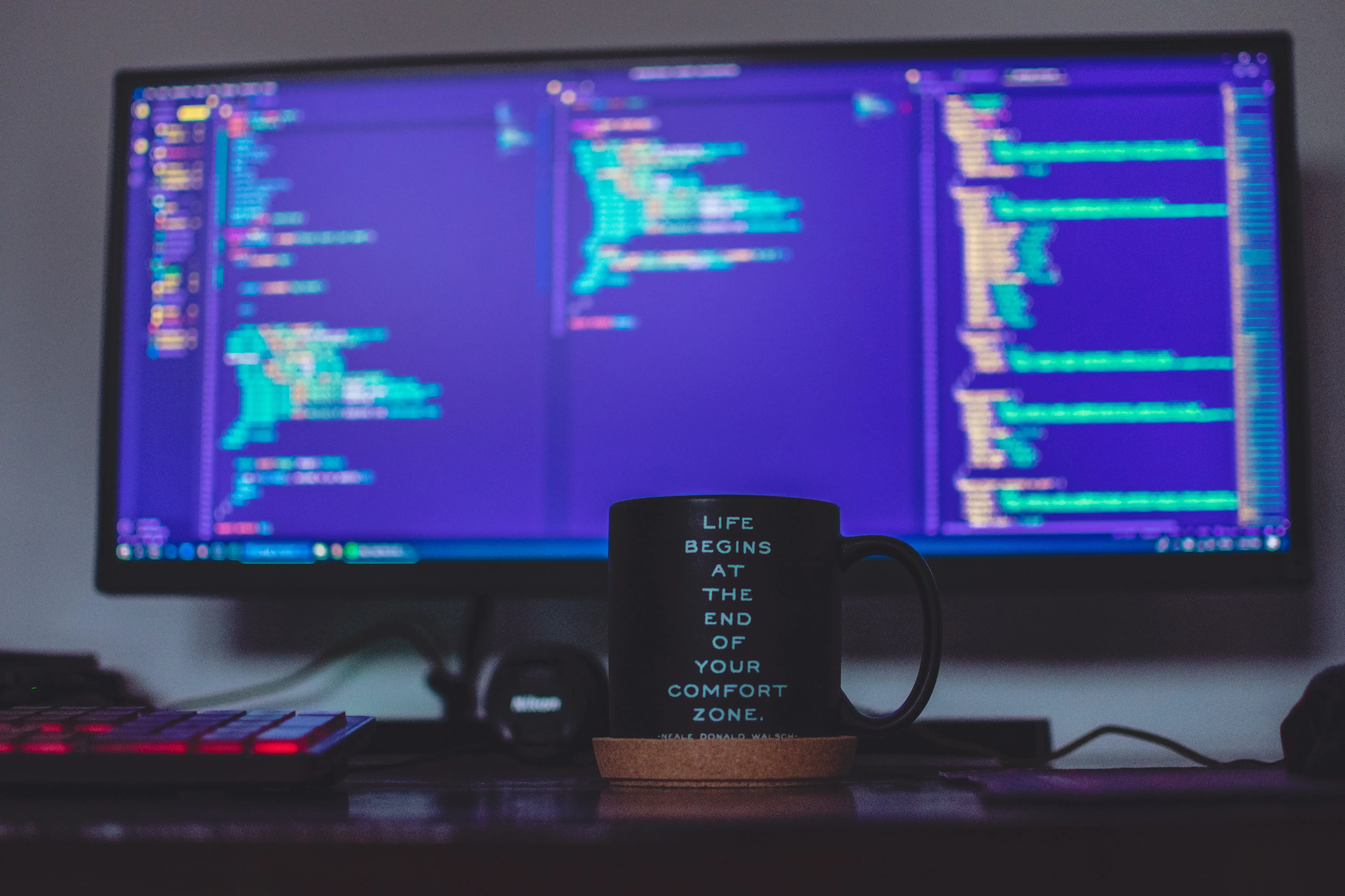 Screen with devlopment code behind a mug of coffee